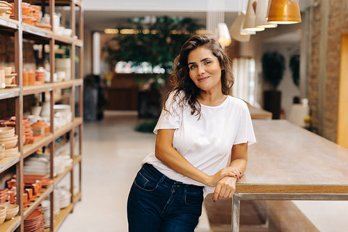 Cheerful young woman looking at the camera in her ceramic store