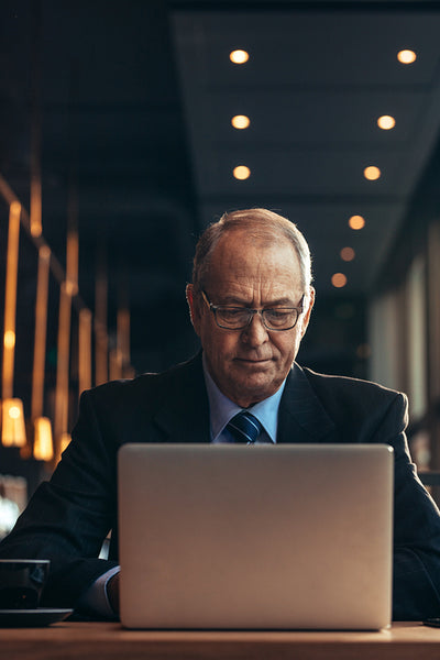 Senior businessman at cafe working on laptop 