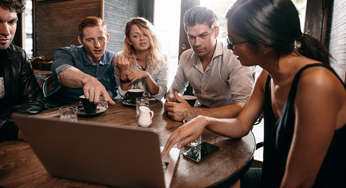 Group of friends at the cafe and looking at laptop