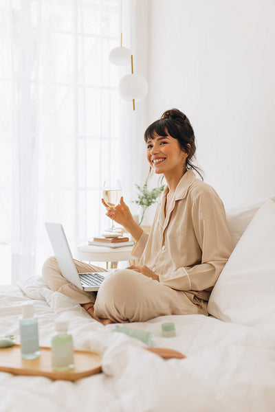 Smiling woman enjoying wine while working from home