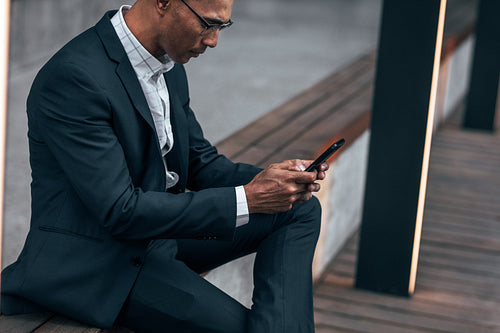 Businessman using mobile phone sitting outdoors