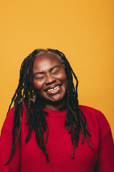 Middle-aged woman with dreadlocks laughing cheerfully in a studio