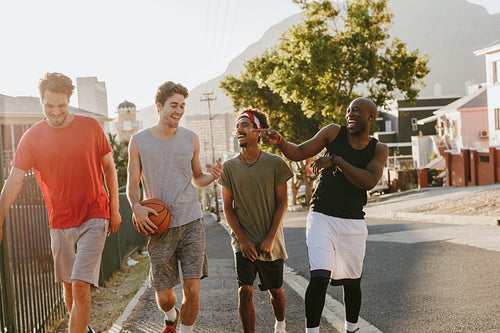 Basketball guys walking on pavement with the ball