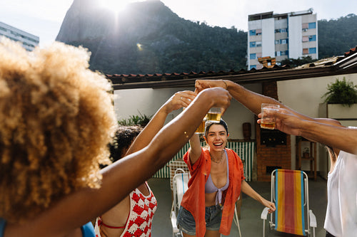 Group of friends toasting drinks on a sunny rooftop gathering