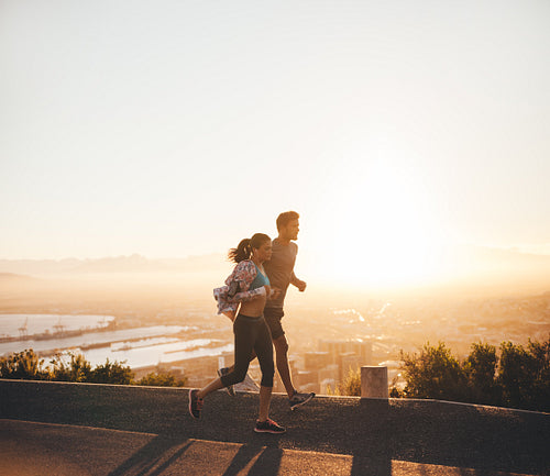 Young couple running together on hillside road