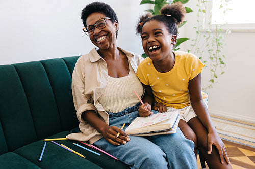 Happy young girl having fun colour drawing with mom
