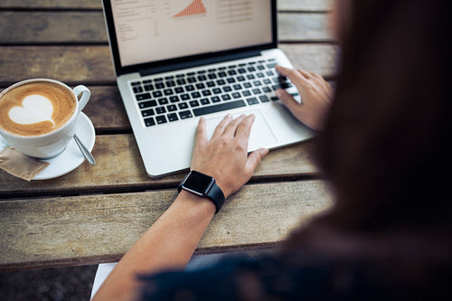 Female with smartwatch using laptop at cafe