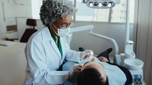 Checkup shows dentist treating senior patient in modern clinic