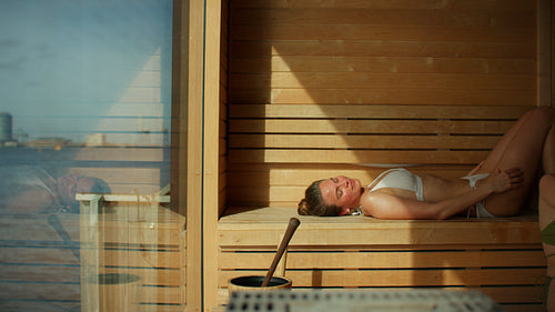 Woman relaxing in sauna at spa with wellness self-care treatment indoors