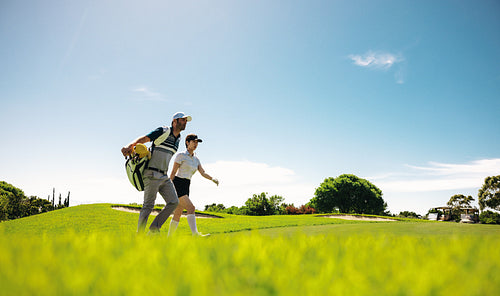 Woman golfer and caddy walking across the golf course during a competition