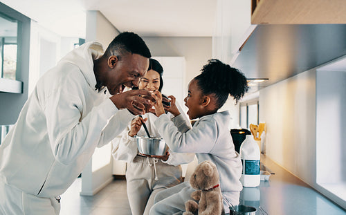 Dad playing with his daughter while mom is cooking in the kitchen