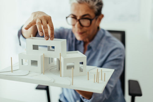 Professional design architect analyzing a 3D model of a house building in her office