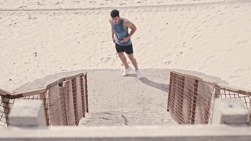 Male runner running up the steps on beach