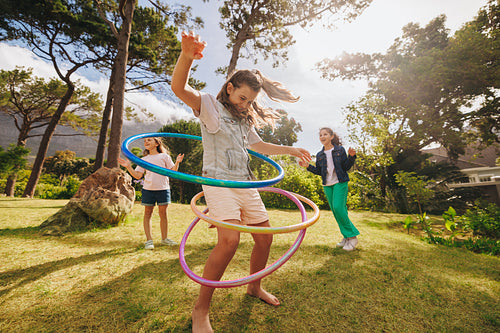Children playing in a park enjoying outdoor activities and using hula hoops