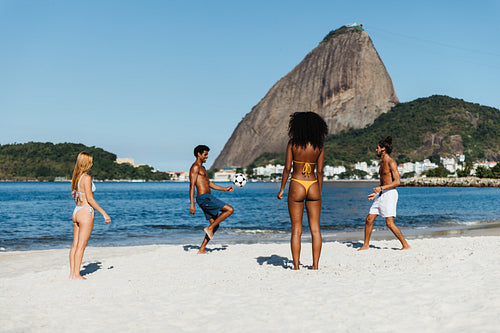 Group of friends playing altinha at Praia do Flamengo beach with Sugarloaf Mountain in the background