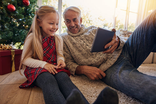 Grandfather and granddaughter having a video on digital tablet during christmas