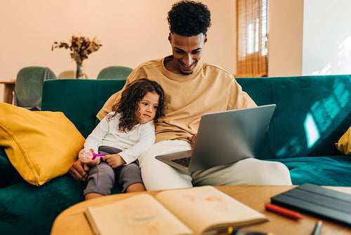 Young single father homeschooling his daughter with a laptop