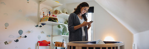 Mother using cellphone after her baby gone asleep in the crib