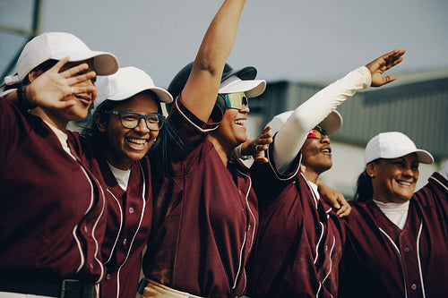Excited women's baseball team with arms raised in team spirit