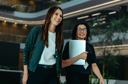 Confident female professionals walking in a modern corporate building