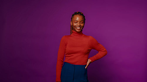 Relaxed young woman smiles on a purple studio backdrop