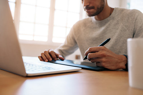 Businessman working on laptop computer using a digital writing pad