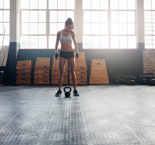 Tough fitness woman with kettle bell on floor