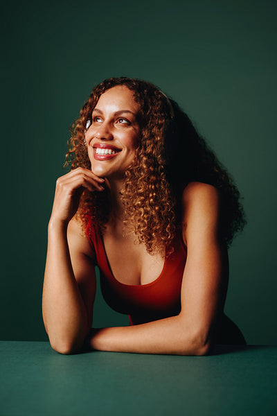 Smiling woman enjoys headphones in a studio portrait against a green background