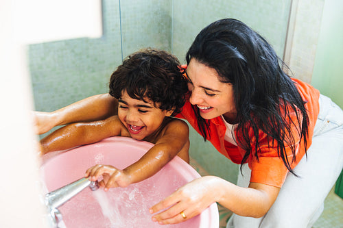 Mother and son bonding while washing hands in a vibrant Latin home
