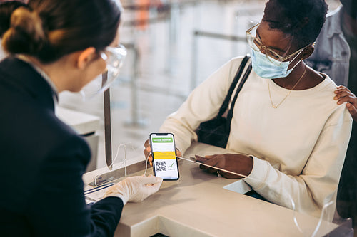Airlines attendant checking vaccine passport of woman
