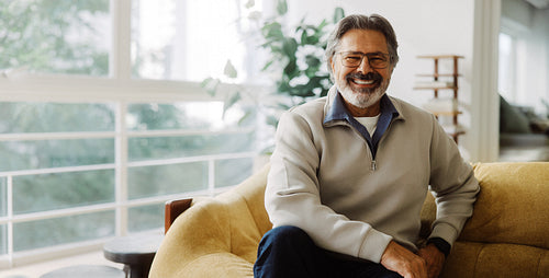 Senior man smiles while sitting at home