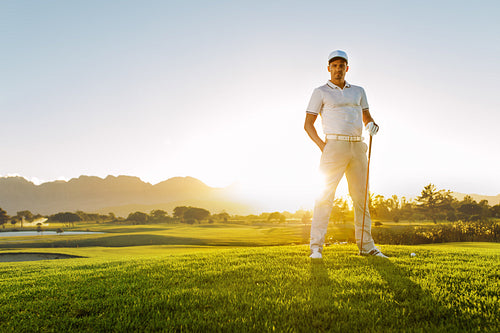 Young male golfer standing on golf course on a summer day