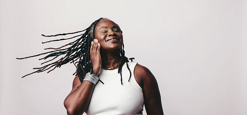 Happy woman with dreadlocks enjoying some music on wireless earbuds