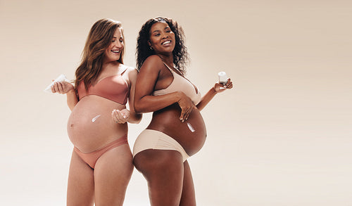 Expecting mothers applying belly skincare cream during the third trimester of pregnancy