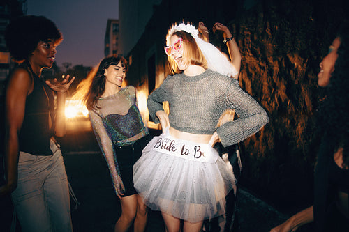 Friends celebrating a bachelorette party with laughter and fun on an evening street