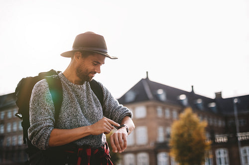 Young tourist looking at wrist watch.