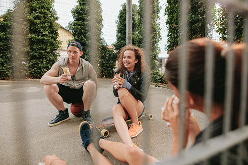 Group of friends sitting at basketball court and having fun
