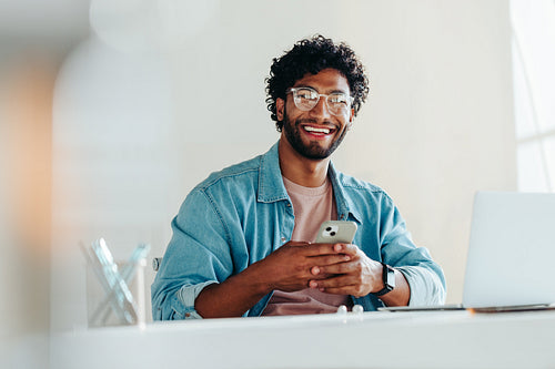 Portrait of a happy professional man working with a smartphone at his office desk