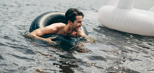 Man swimming in water using a rubber tube