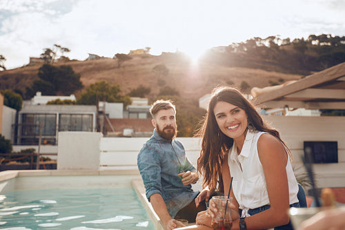 Woman sitting by pool with friends having a party