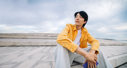 Young man sitting outdoors looking thoughtful on steps
