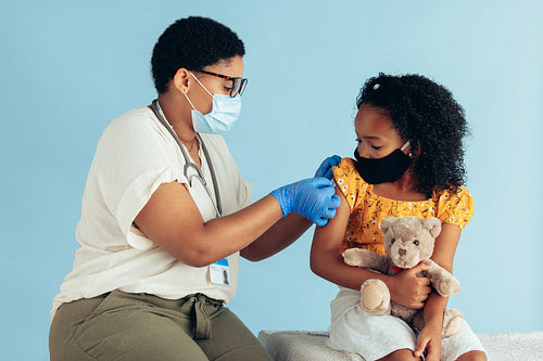 Doctor giving vaccine to a girl during pandemic