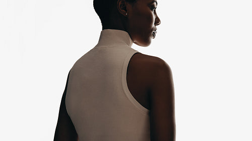 Elegant woman in sleeveless top posing with a minimalistic white background