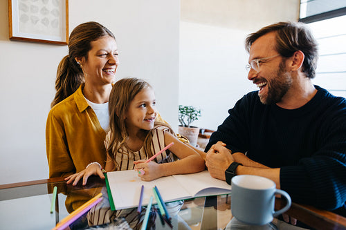 Family at home shares a smile around the table.