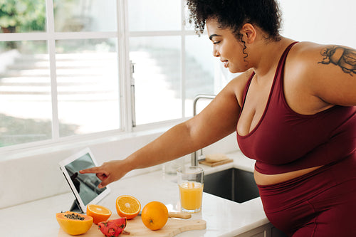 Fitness woman checking juice recipe on digital tablet