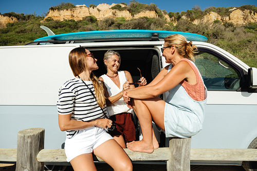 Group of friends enjoying time near a camper van during a surf trip