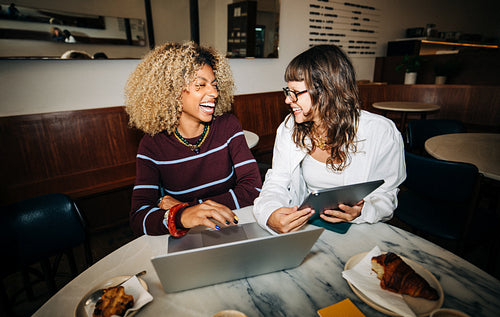 Women friends collaboration over laptop in café