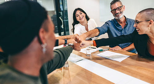 Diverse group of businesspeople bringing their fists together in a boardroom