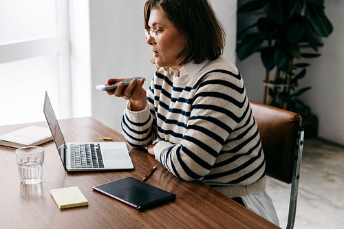 The smartphone keeps the woman in communication while she works at her desk