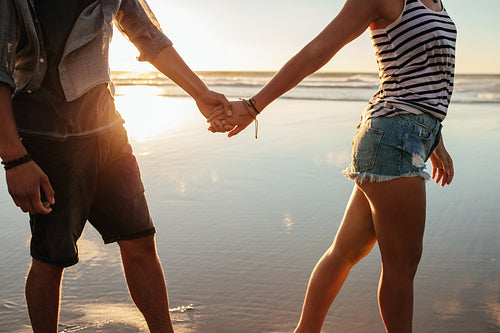 Couple holding hands and walking on the shore